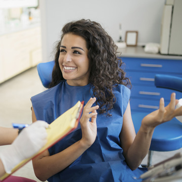 Attractive young Caucasian woman talking to her dentist