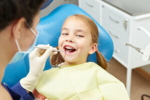 Little girl sitting in the dentist's office. Pediatric dentistry. Smiling child and doctor.